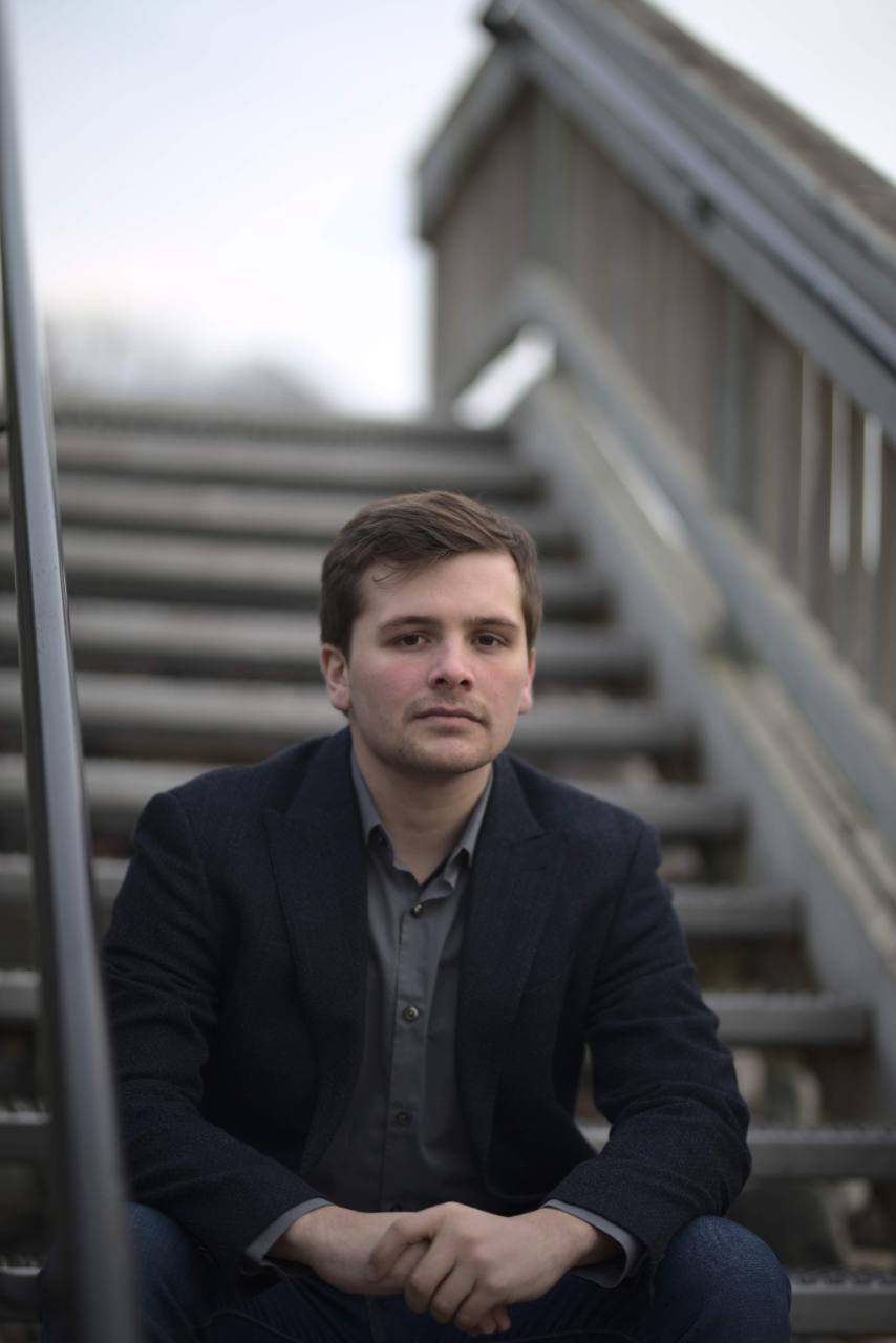 Hunter Jacobs seated on outdoor steps in a navy blazer